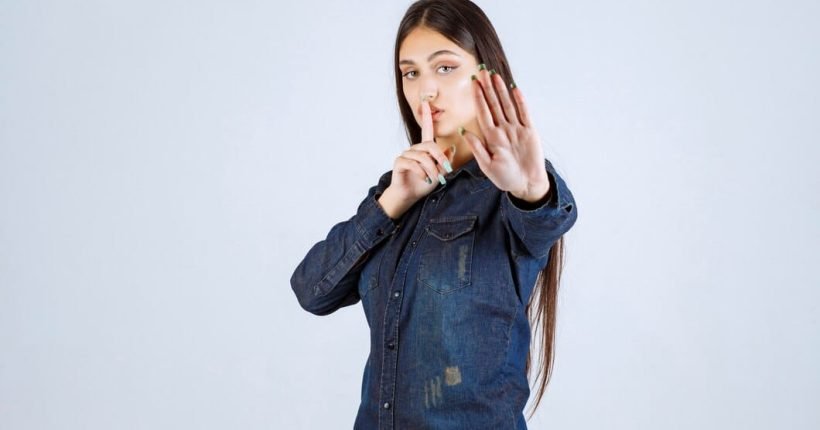 young-woman-denim-shirt-pointing-her-mouth-asking-be-quiet_144627-52148